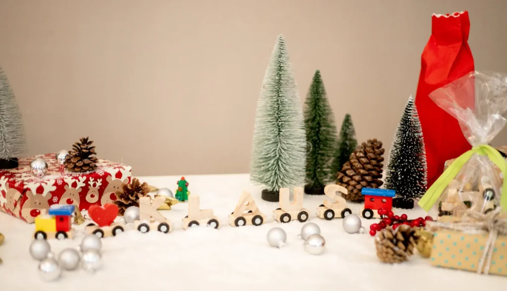 Namenszug aus Holz mit dem Namen Klaus zwischen Tannenbäumen und Weihnachtsdeko